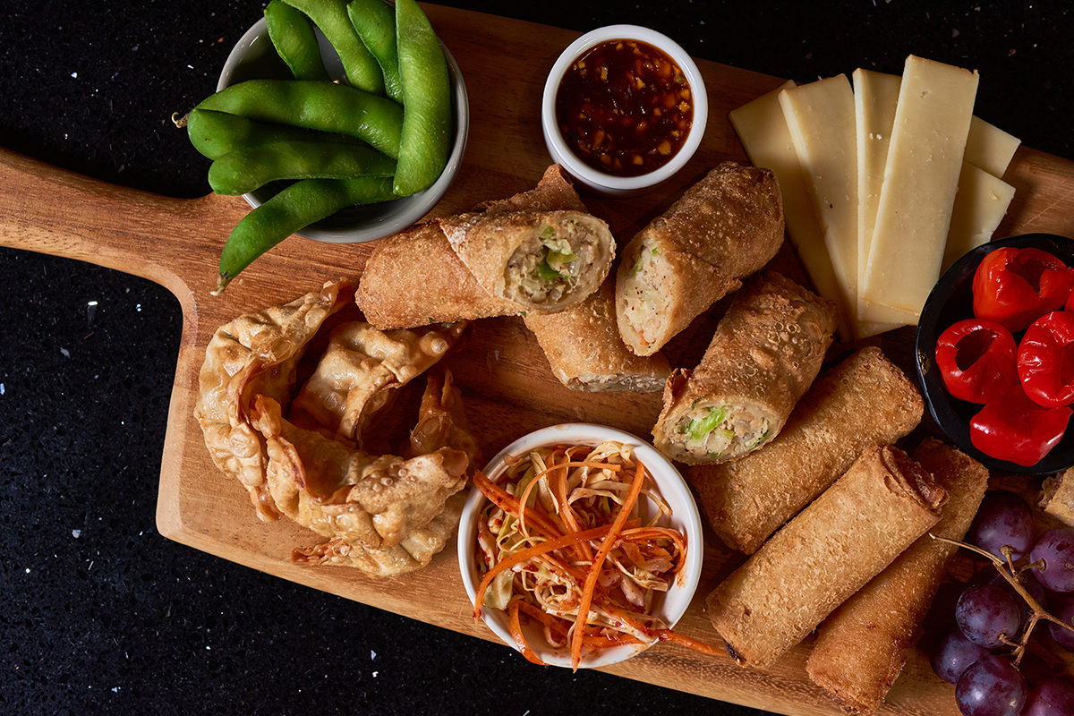 appetizer platter with fried dumplings, egg rolls, cheese, various sauces and vegetables